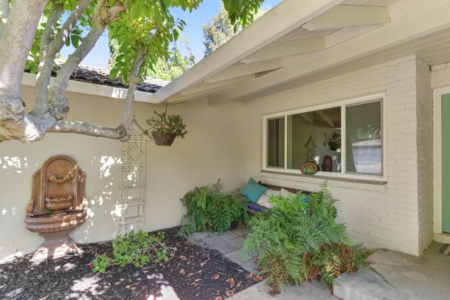 a vase of flowers sitting on a floor in front of a house