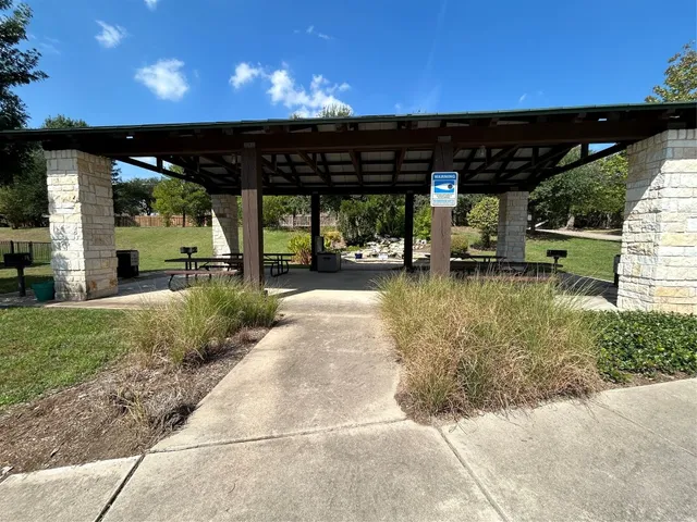 a view of swimming pool with outdoor seating and covered with trees in the background