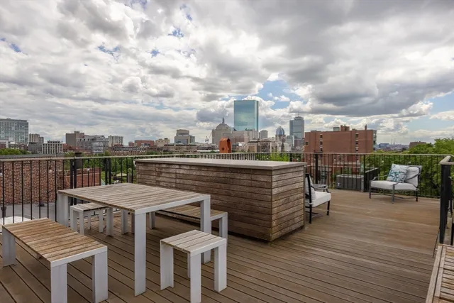 a view of a rooftop deck with chairs and wooden floor
