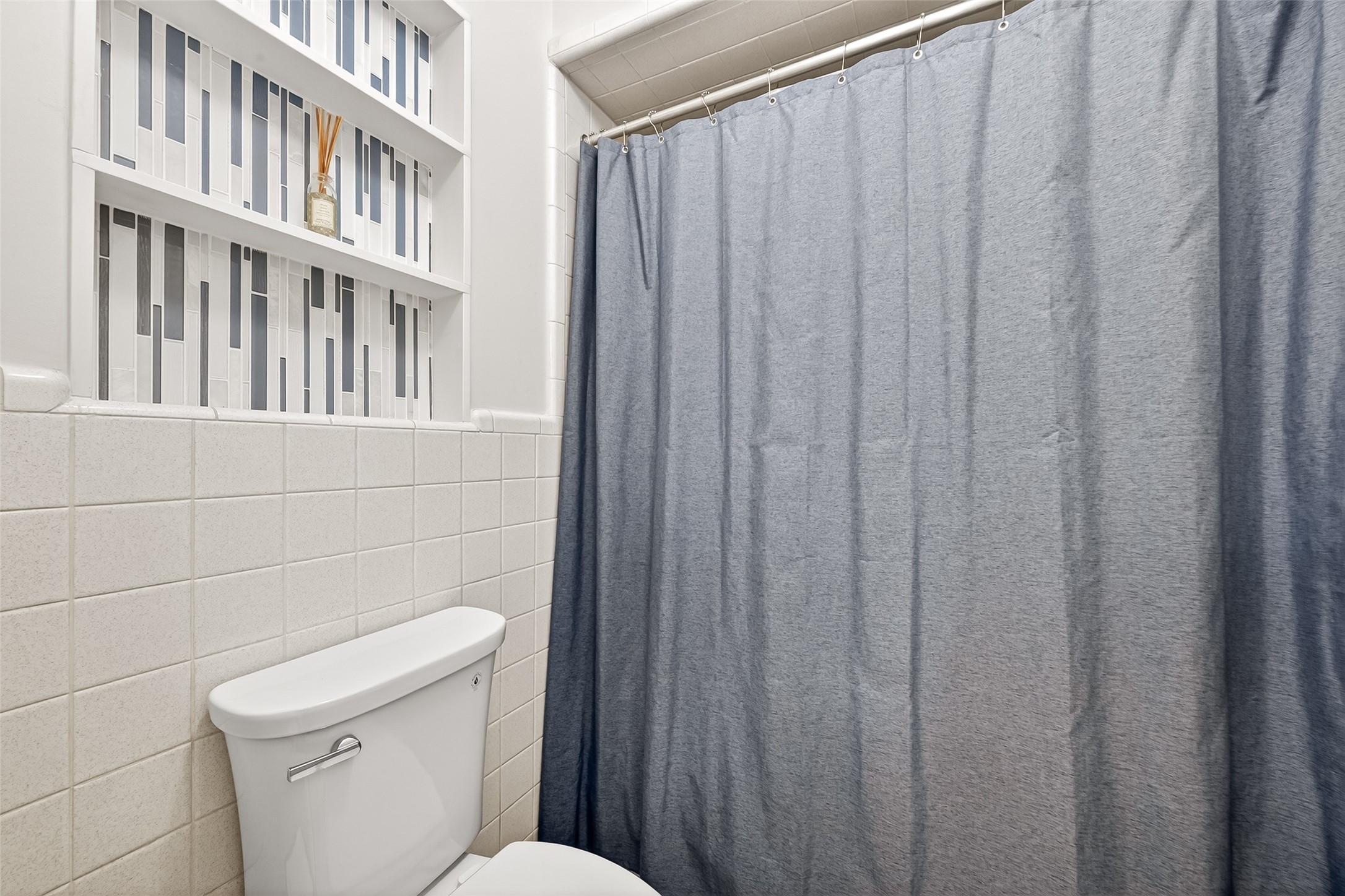 2610 Teague Road Houston, TX 77080 - Photo 37 of 49 This bathroom features a neatly tiled wall and a shower-tub combination. Built-in shelving provides stylish storage, accented with geometric tile patterns.