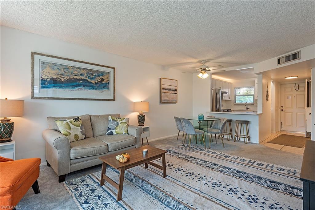 200 Forest Lakes Boulevard, Unit 201 Naples, FL 34105 - Photo 4 of 12 a living room with furniture and a table