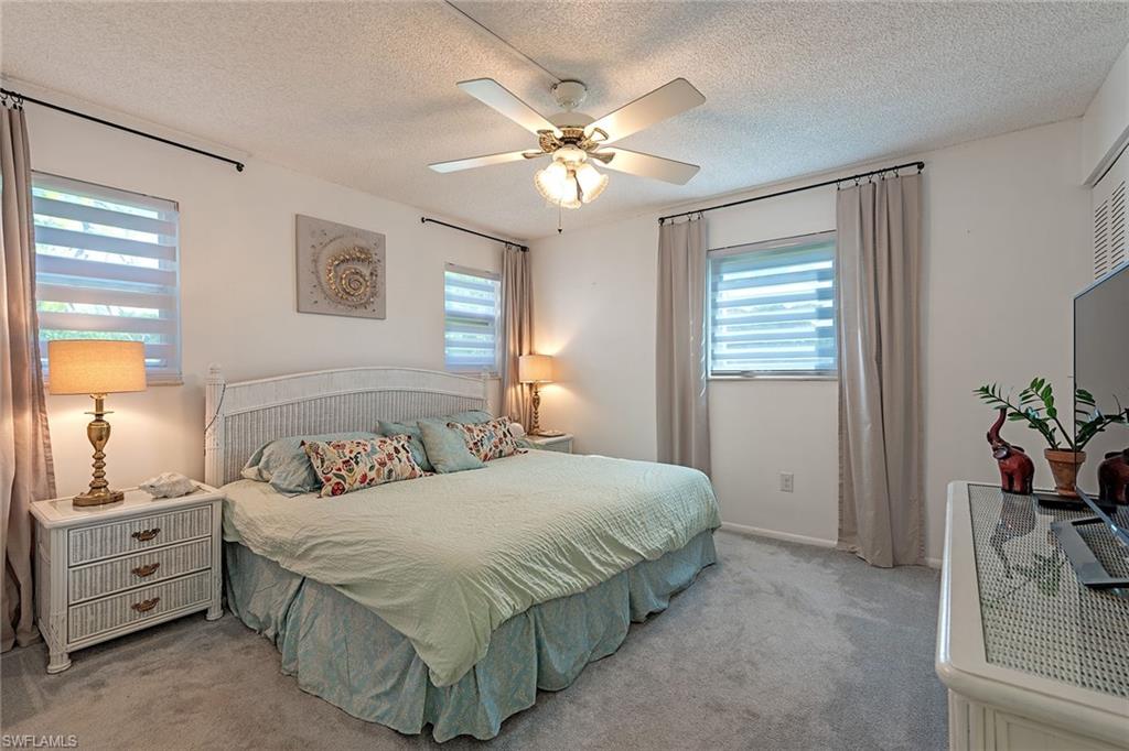 200 Forest Lakes Boulevard, Unit 201 Naples, FL 34105 - Photo 10 of 12 a bedroom with a bed and a chandelier