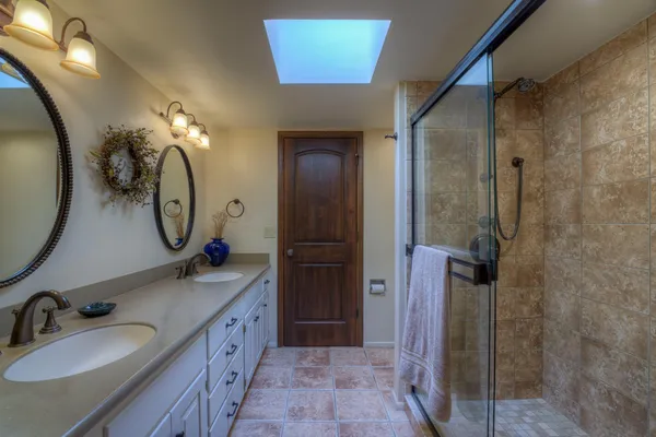 a spacious bathroom with a double vanity sink mirror and shower