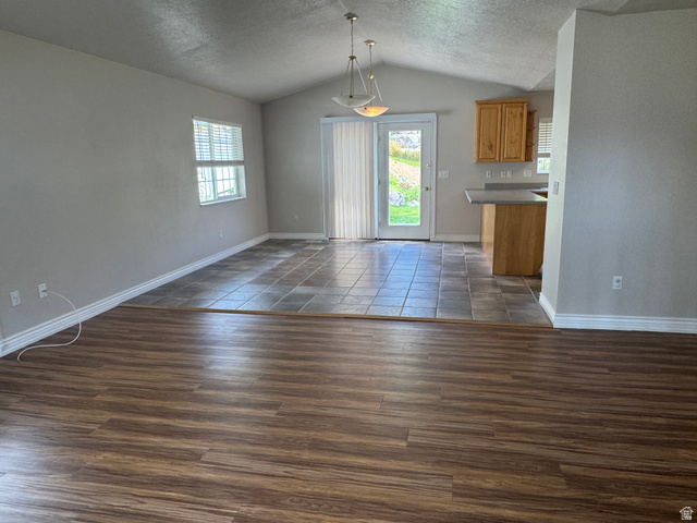 88 Canterbury Lane Logan, UT 84321 - Photo 8 of 37 Open-concept living space featuring vaulted ceilings and a dual-material flooring design