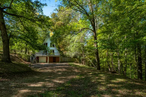 a view of a house with a small yard and large trees