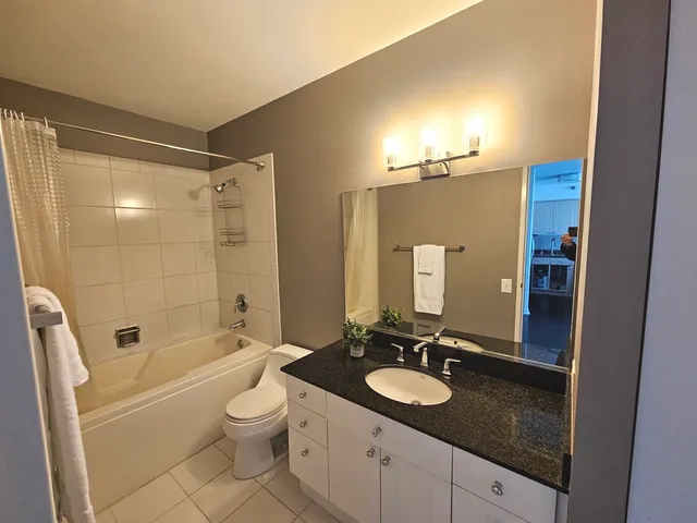 a bathroom with a granite countertop sink toilet a large mirror a bathtub and shower