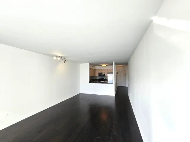 a view of a big room with wooden floor and windows