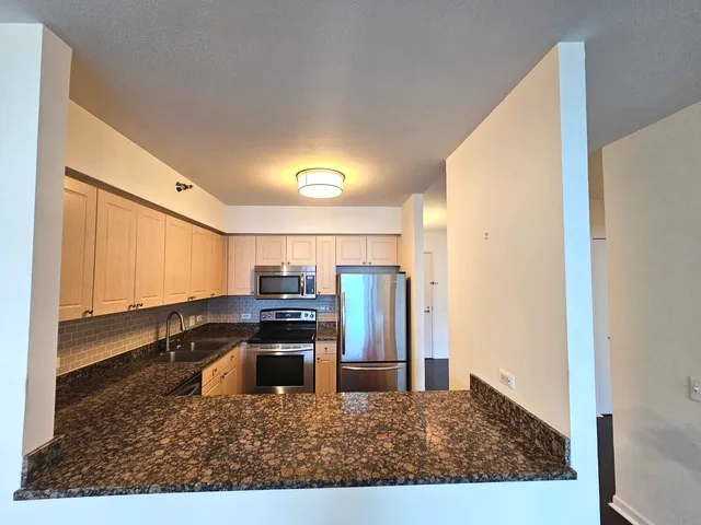 a kitchen with stainless steel appliances kitchen island granite countertop a refrigerator and a sink