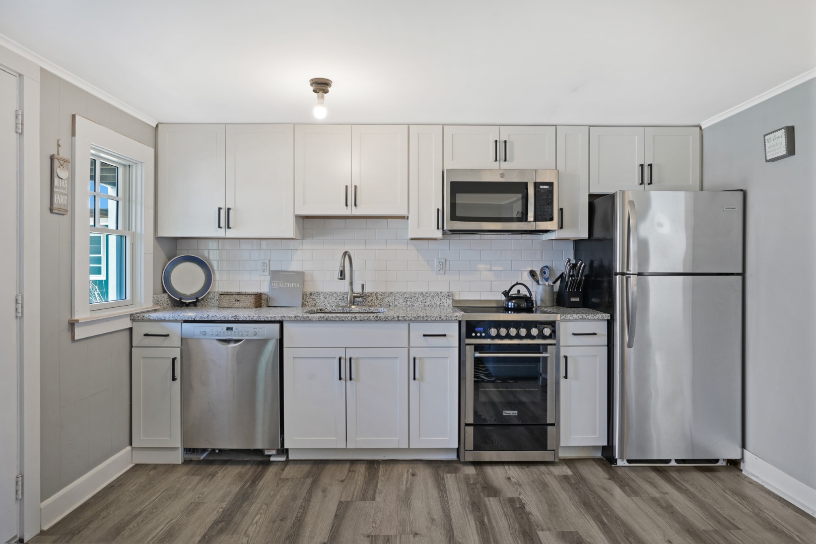 20 Peases Point Way North, Unit 4 Edgartown, MA 02539 - Photo 5 of 11 a kitchen with granite countertop a refrigerator stove and white cabinets