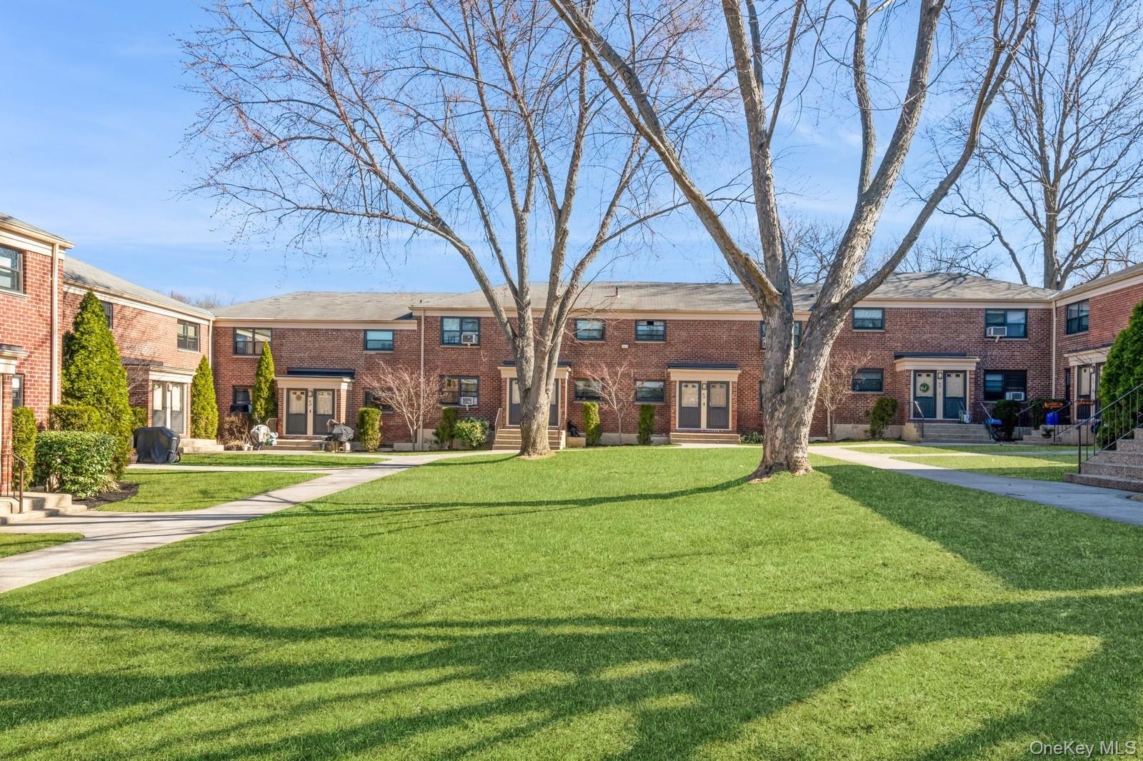 74-67 220th Street, Unit 101A Queens, NY 11364 - Photo 1 of 15 View of property's community featuring a lawn