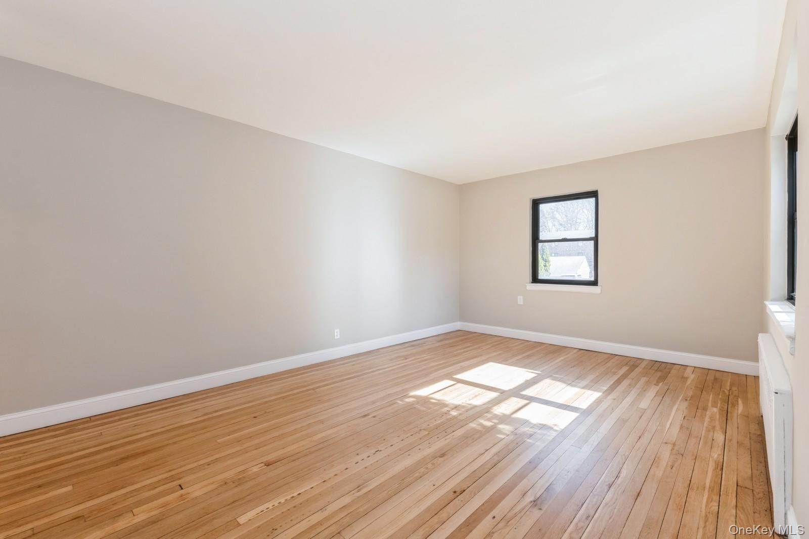 74-67 220th Street, Unit 101A Queens, NY 11364 - Photo 3 of 15 Empty room with baseboards and light wood-style floors