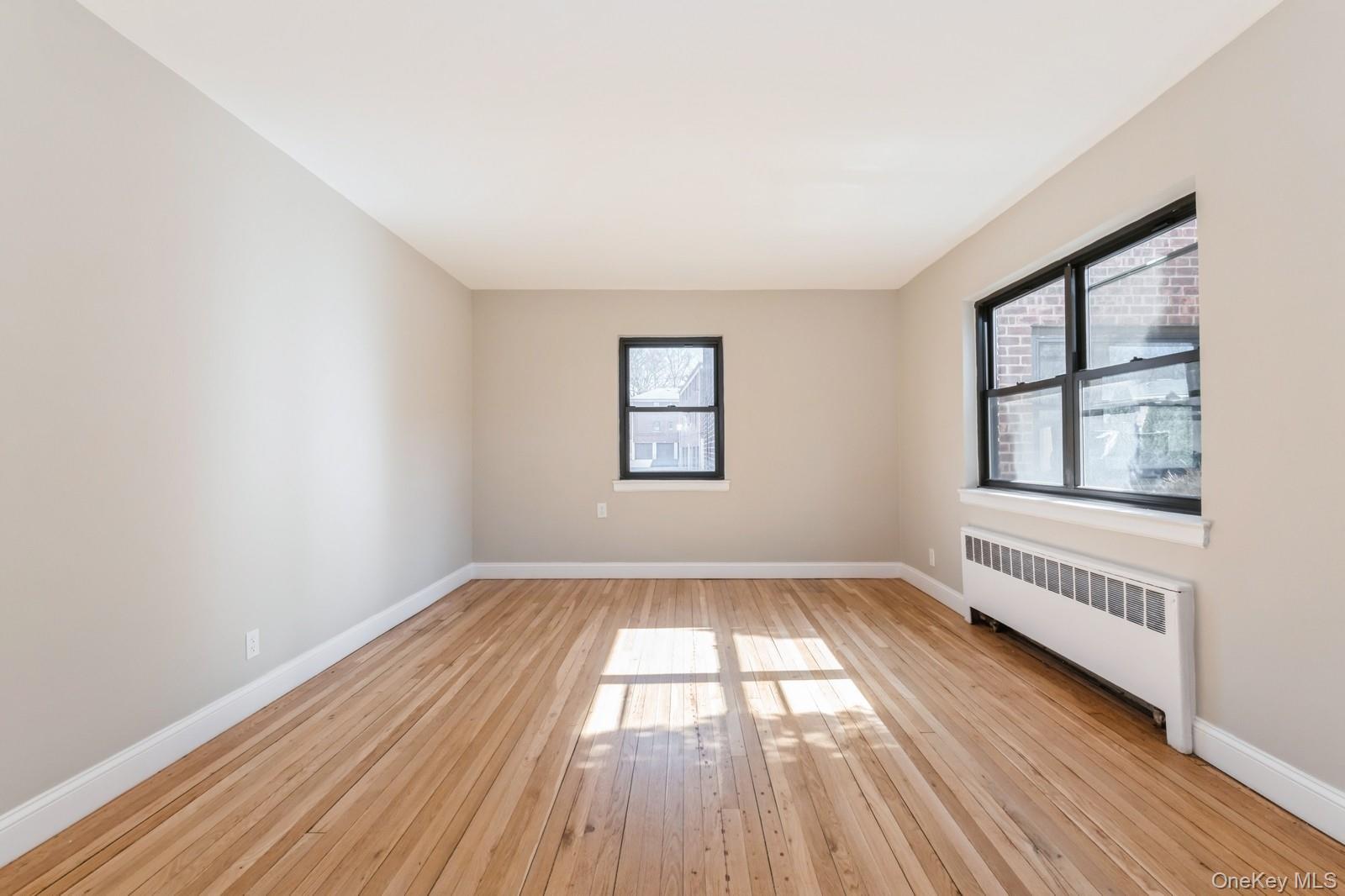 74-67 220th Street, Unit 101A Queens, NY 11364 - Photo 4 of 15 Unfurnished room featuring baseboards, radiator, and light wood-style flooring