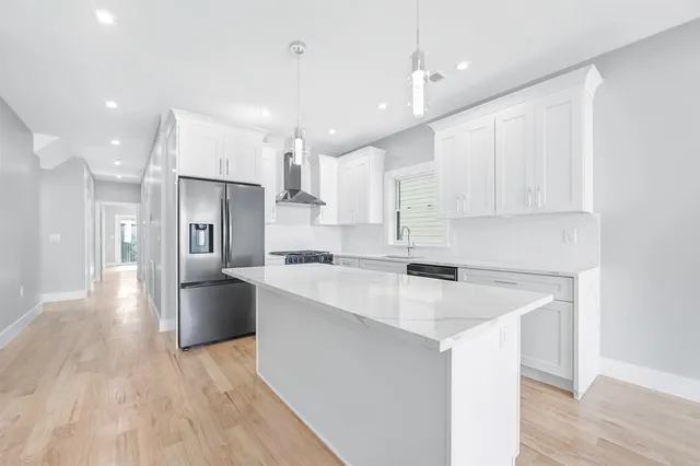 a kitchen with stainless steel appliances kitchen island a refrigerator sink and cabinets