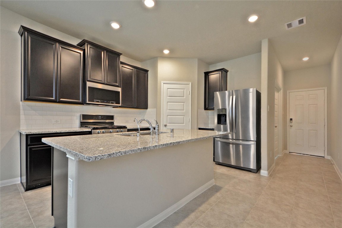 1015 Modesto Drive Rosharon, TX 77583 - Photo 13 of 37 Beautifully designed gourmet kitchen featuring granite countertops, a large eat in island, rich cabinetry, and stainless-steel appliances, including Brand New Side by Side Stainless Steel Refrigerator! Bright lighting and open layout make this space perfect for cooking and entertaining. A dream kitchen awaits, CALL NOW!
