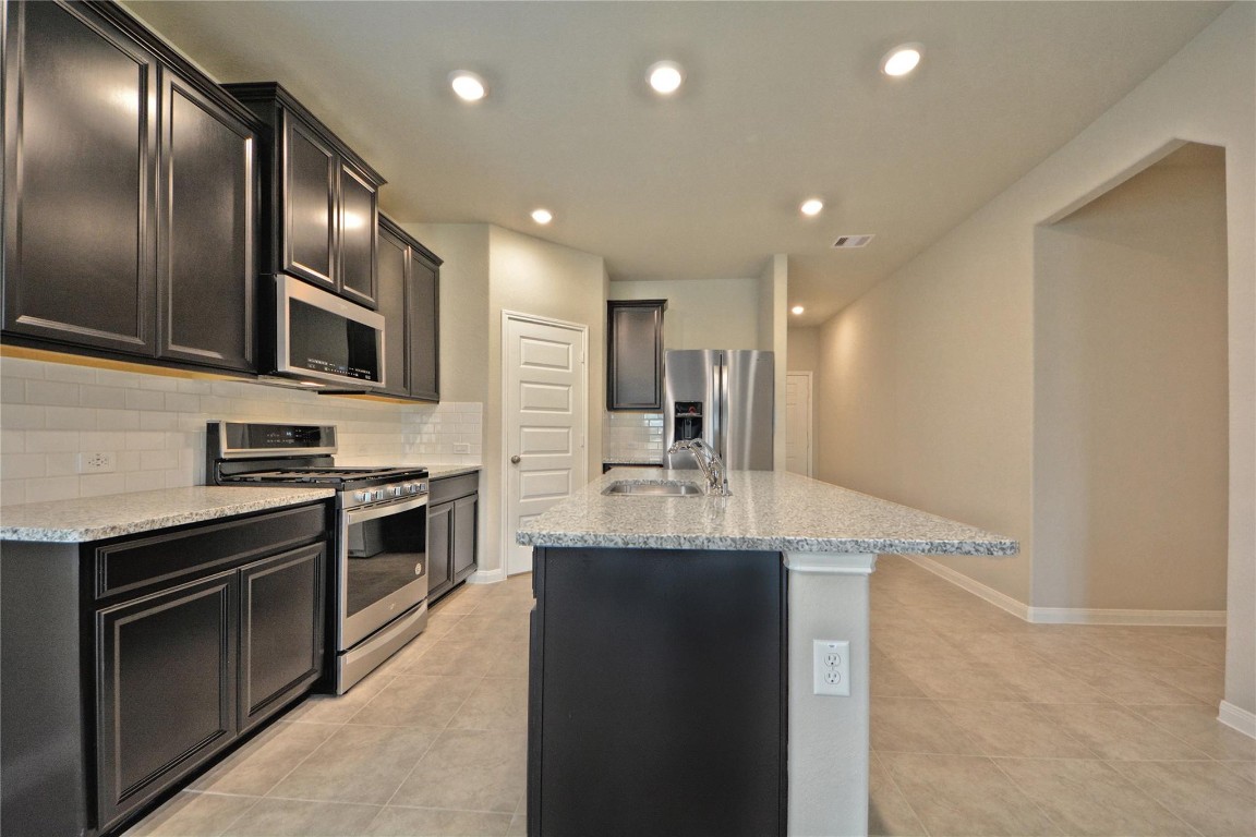 1015 Modesto Drive Rosharon, TX 77583 - Photo 14 of 37 Another stunning angle of the kitchen showcasing the expansive counter space, sleek cabinetry, and modern finishes! 5 Burner stainless gas range with large oven for those holidays cooking! Enjoy the perfect blend of style and functionality with plenty of room for meal prep and gathering. Large walk-in pantry and so much more to enjoy in this amazing home! DO NOT FORGET A NEW SIDE BY SIDE STAINLESVacant and ready for your memories! S STEEL REFRIGERATOR!