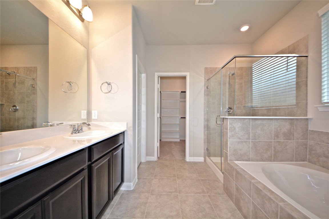 1015 Modesto Drive Rosharon, TX 77583 - Photo 18 of 37 Luxurious primary bathroom featuring dual vanities, elegant finishes, soaking tub, and a separate glass enclosed shower! Enjoy a spa like experience every day with plenty of space and comfort. Make this home yours today!