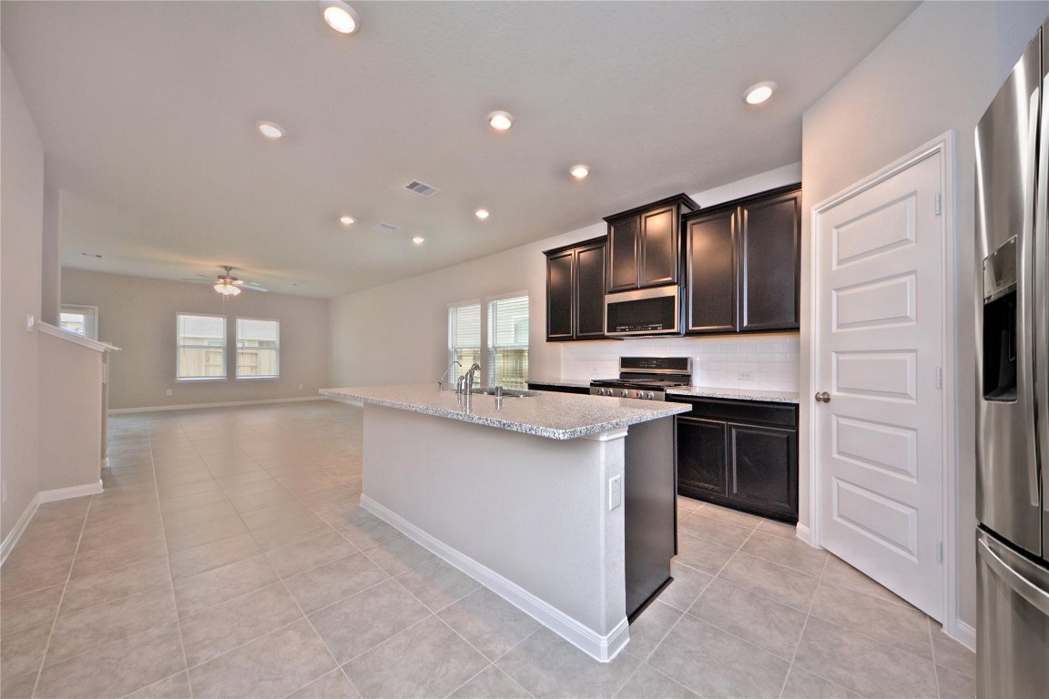 1015 Modesto Drive Rosharon, TX 77583 - Photo 7 of 37 Gorgeous gourmet kitchen featuring a large eat in island with plenty of seating, sleek granite countertops, rich cabinetry, and stainless steel appliances! Bright recessed lighting and an open layout make this kitchen perfect for both everyday living and entertaining. A true heart of the home!