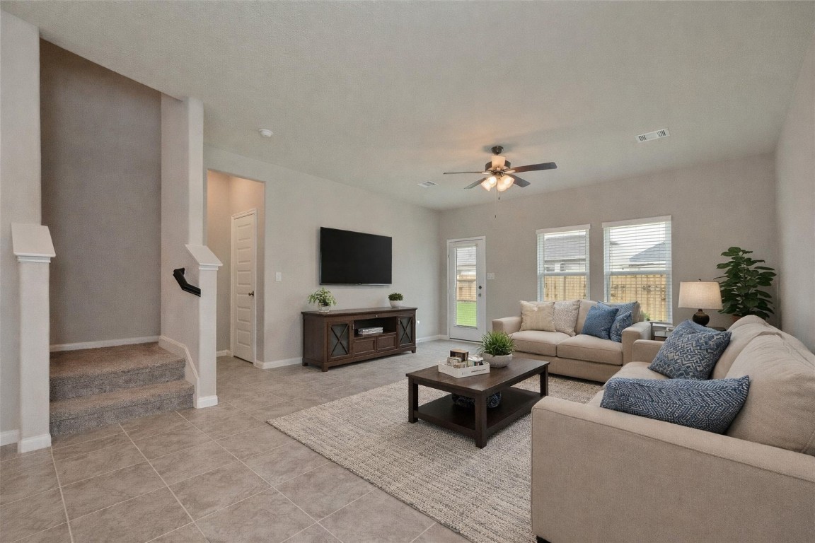 1015 Modesto Drive Rosharon, TX 77583 - Photo 10 of 37 Another view of the open layout showcasing the seamless flow between living spaces and the staircase leading upstairs! Thoughtfully designed for both comfort and functionality, this home offers room for everyone. Beautiful large tile flooring for easy upkeep! *Virtually Staged*