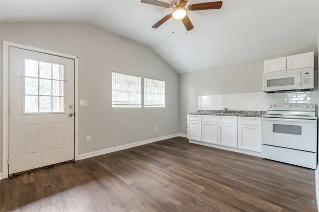 a kitchen with granite countertop white cabinets and white appliances