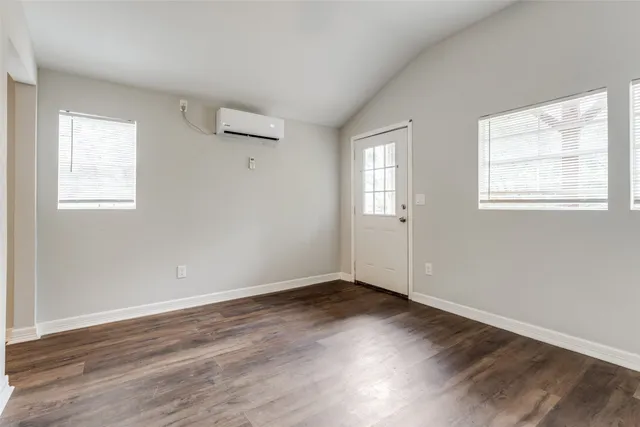 an empty room with wooden floor fan and windows