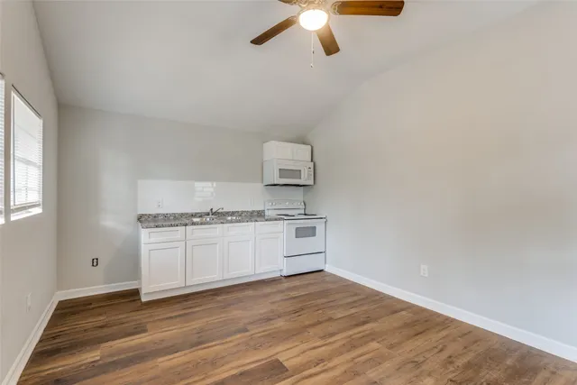 a kitchen with granite countertop white cabinets and white appliances