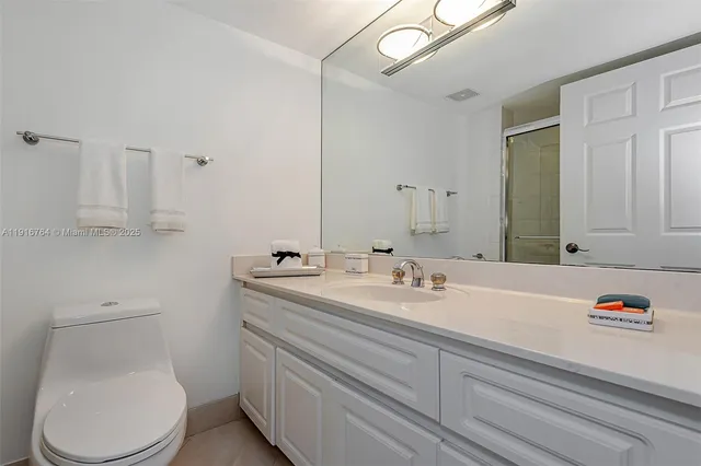 a bathroom with a granite countertop toilet sink and mirror