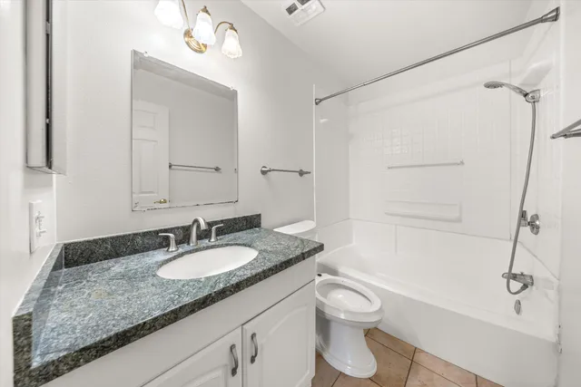 a bathroom with a granite countertop sink toilet a shower and a mirror