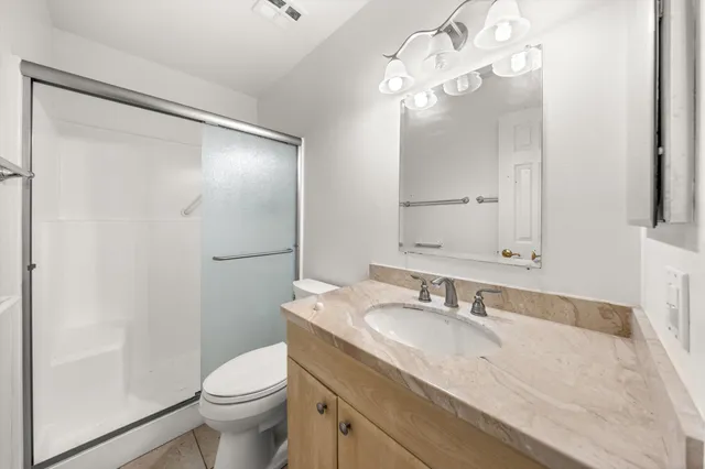 a bathroom with a granite countertop sink toilet and shower