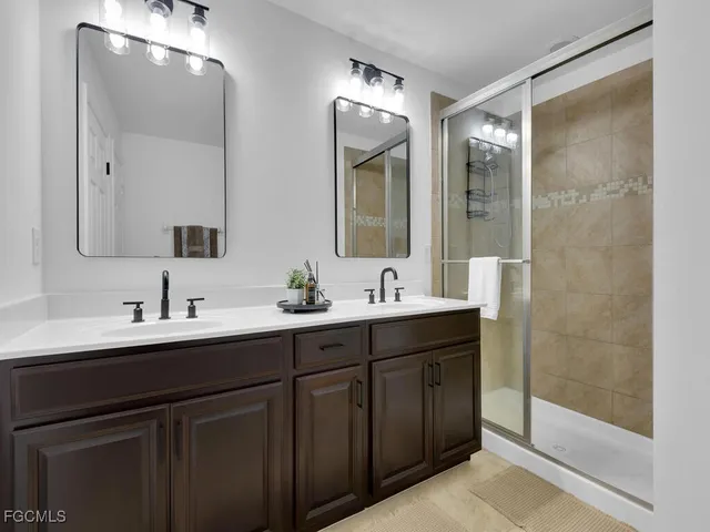 a bathroom with a double vanity sink mirror and shower