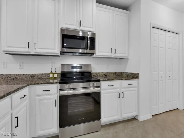 a kitchen with white cabinets and stainless steel appliances