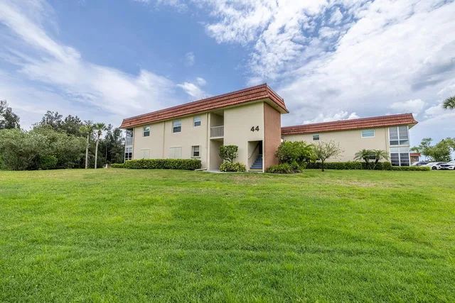 a view of a white house with a big yard and potted plants