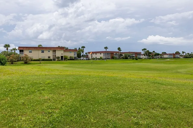 a sign that is sitting in front of a big building with trees