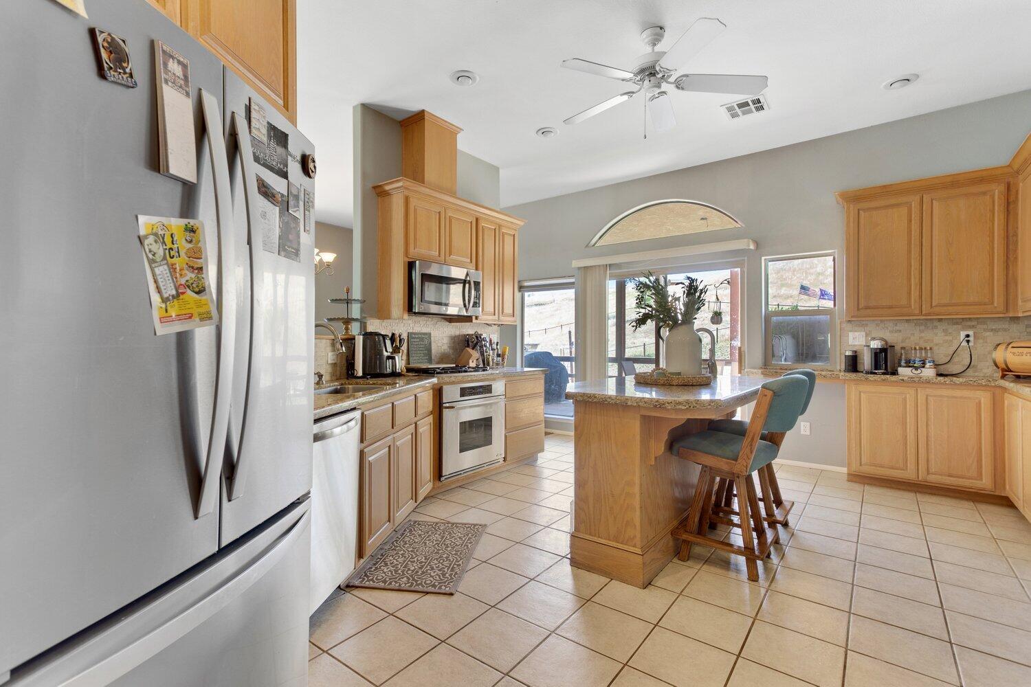 19510 Banducci Road Tehachapi, CA 93561 - Photo 19 of 75 a kitchen with stainless steel appliances granite countertop a refrigerator a sink a stove and white cabinets