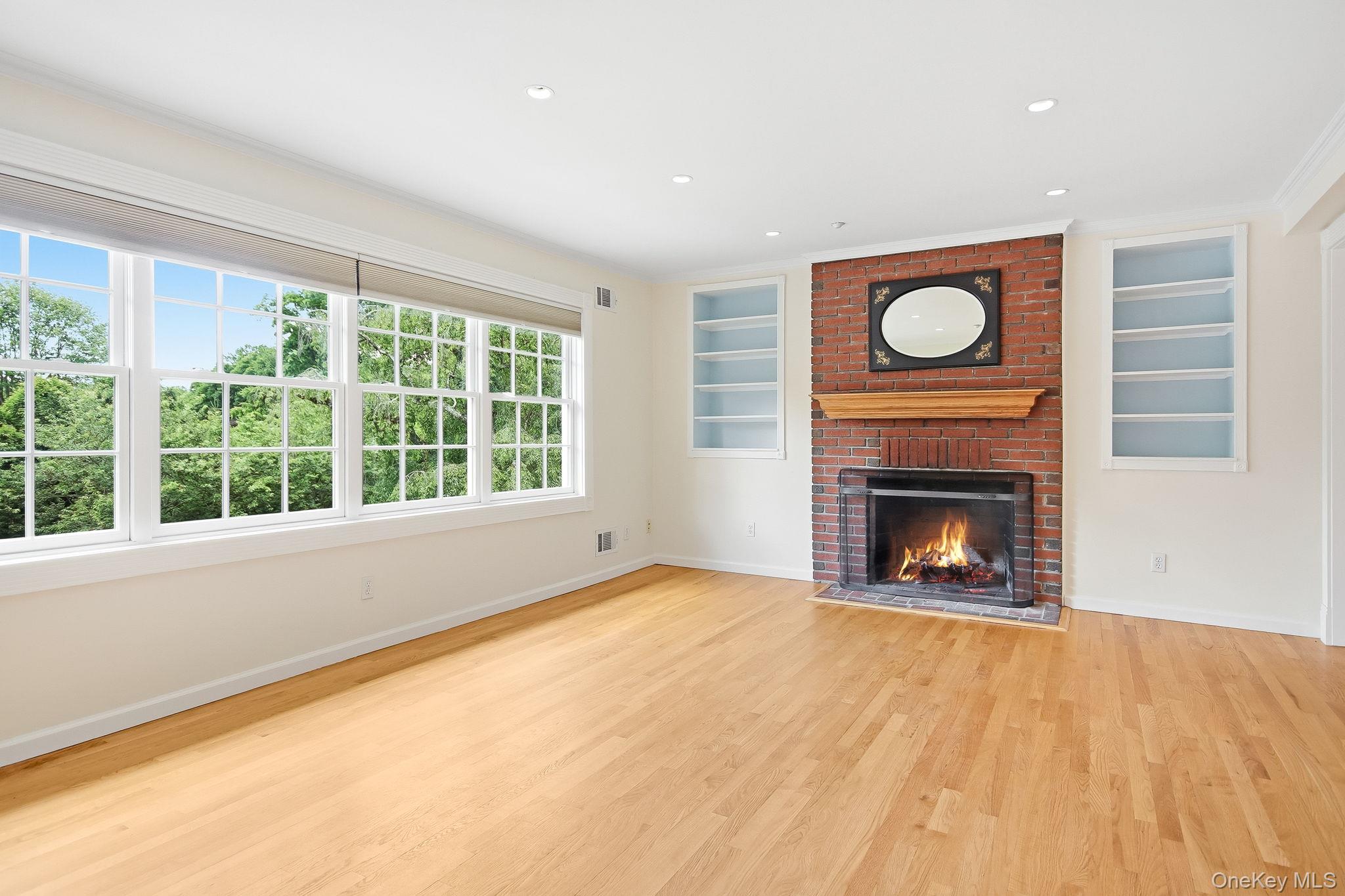 26 Century Ridge Road Purchase, NY 10577 - Photo 8 of 50 Spacious living room featuring hardwood flooring, a brick fireplace with a wood mantel, and built-in shelving