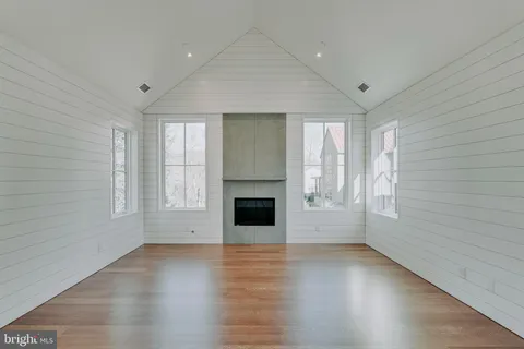 an empty room with windows and fireplace