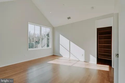 a view of an empty room with wooden floor and window