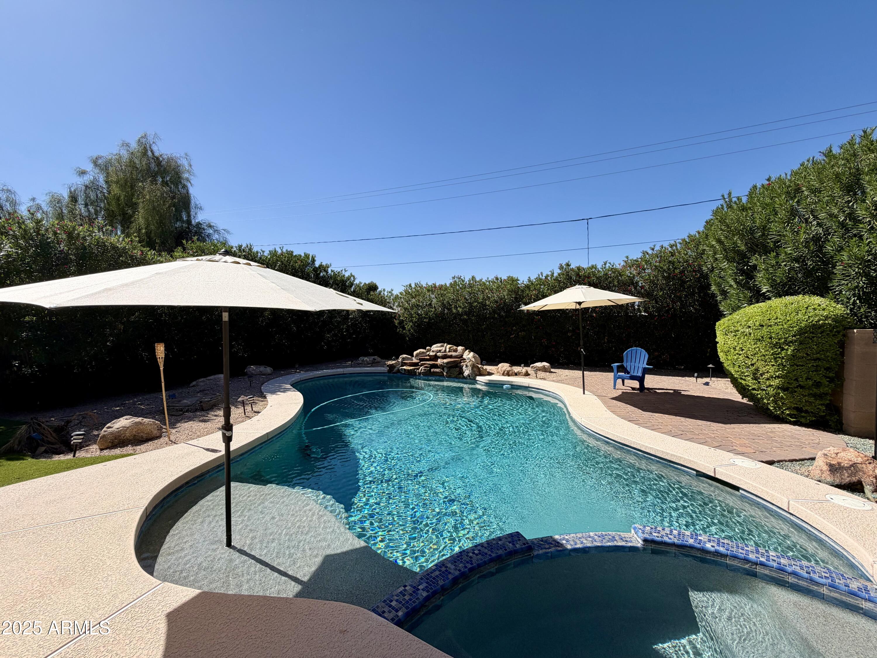 a backyard of a house with table and chairs under an umbrella