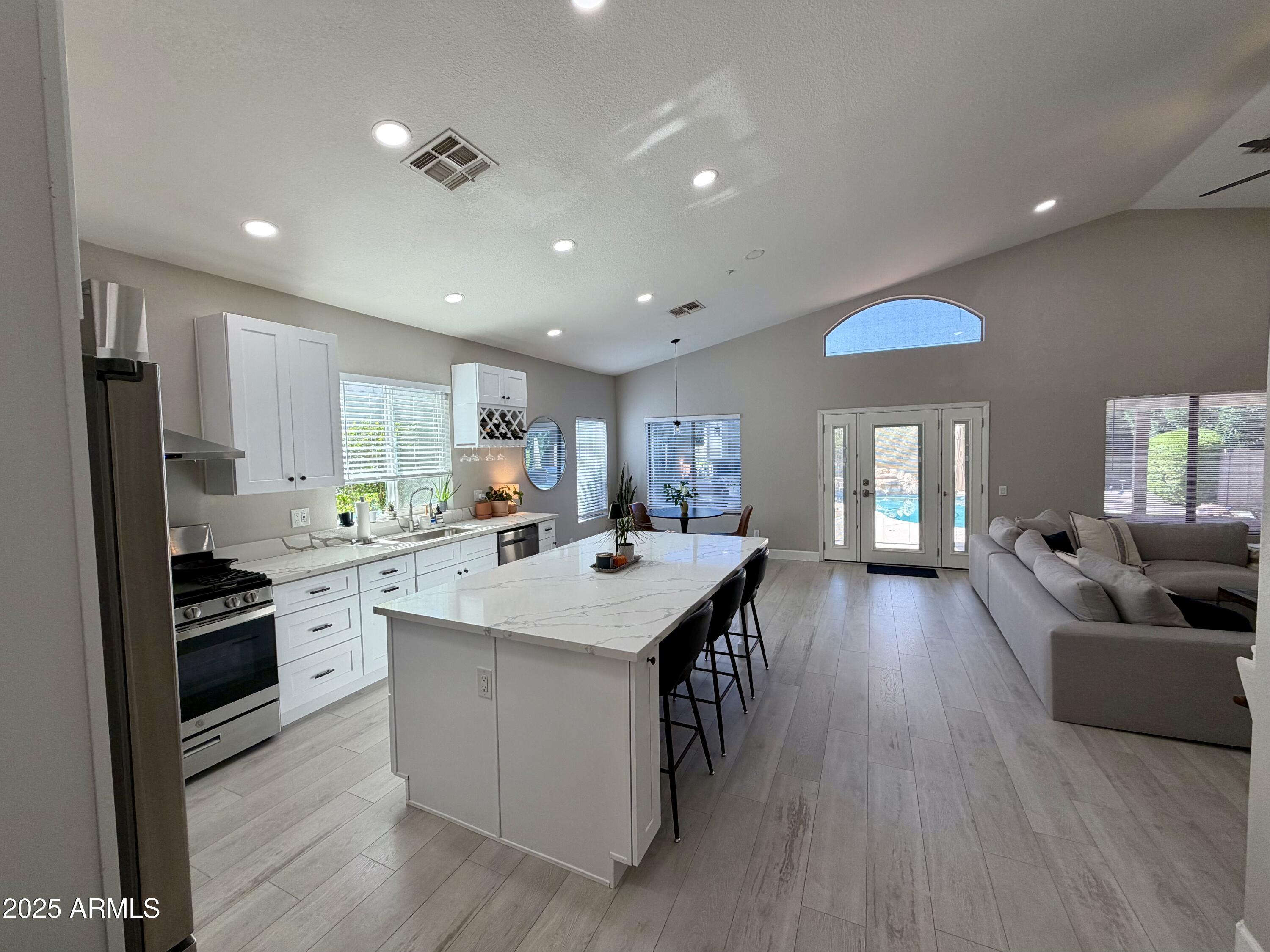 3068 North 83rd Place Scottsdale, AZ 85251 - Photo 11 of 46 a large kitchen with kitchen island a stove a sink a refrigerator and cabinets