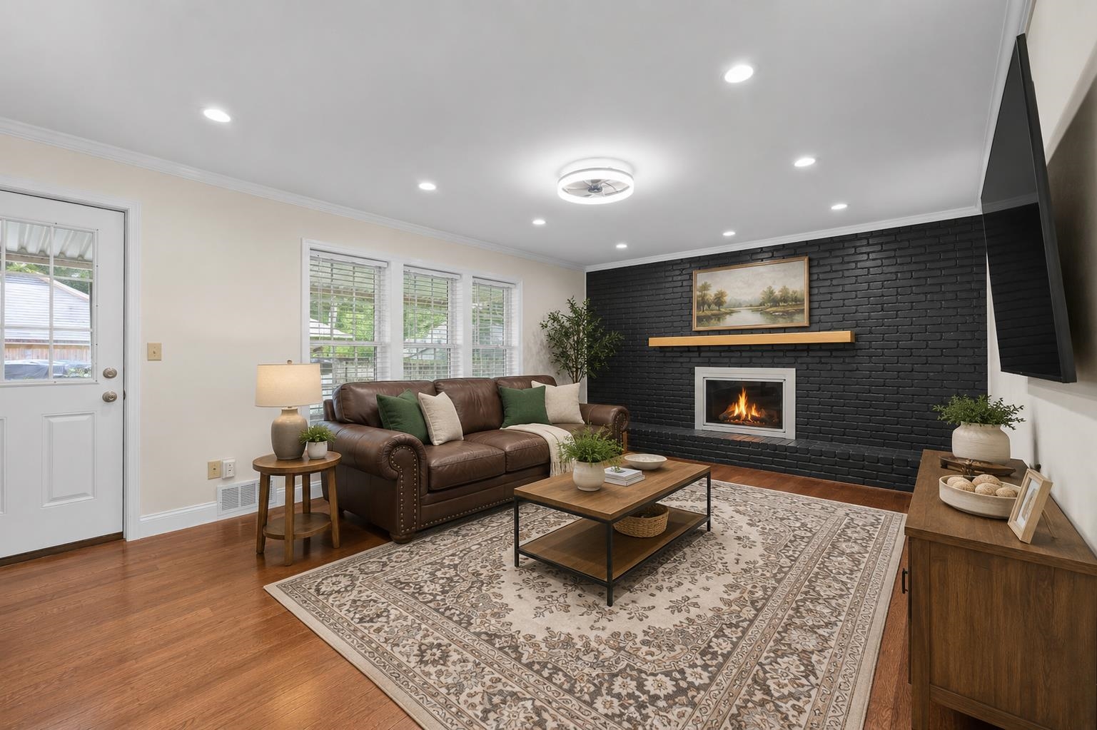 2218 Riverdale Road Germantown, TN 38138 - Photo 4 of 40 Beautifully updated great room showcasing a dramatic painted brick fireplace, recessed lighting, and rich hardwood-style flooring. Virtually staged to highlight the spacious layout, creating the perfect setting for relaxing evenings and entertaining.