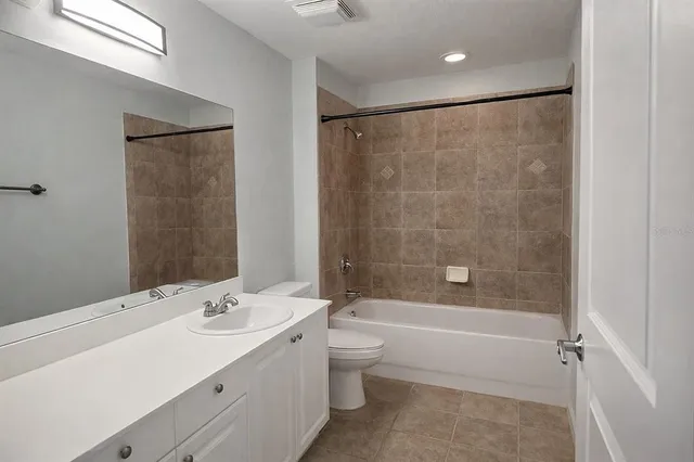 a bathroom with a bathtub shower sink vanity mirror and toilet