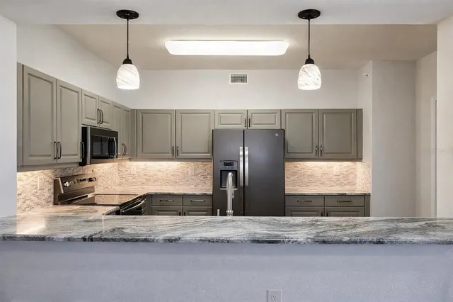 a kitchen with kitchen island granite countertop a sink and a refrigerator