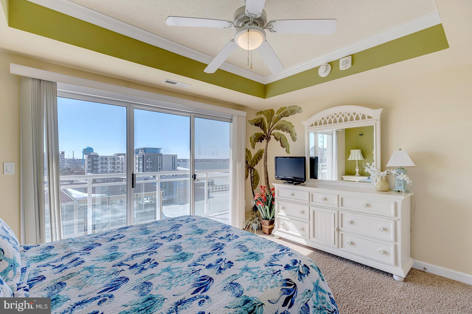 4601 Coastal Highway, Unit 403 Ocean City, MD 21842 - Photo 32 of 56 a bedroom with a large bed and a flat tv screen on dresser
