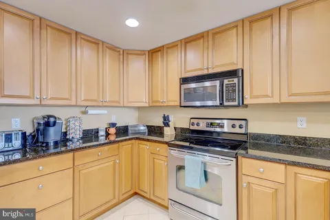 a kitchen with granite countertop white cabinets and stainless steel appliances
