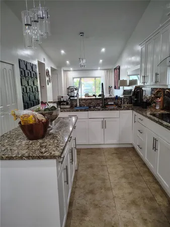 a large kitchen with a counter top space a sink stainless steel appliances and cabinets