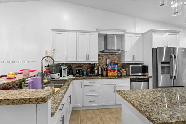a kitchen with granite countertop a sink stove and refrigerator