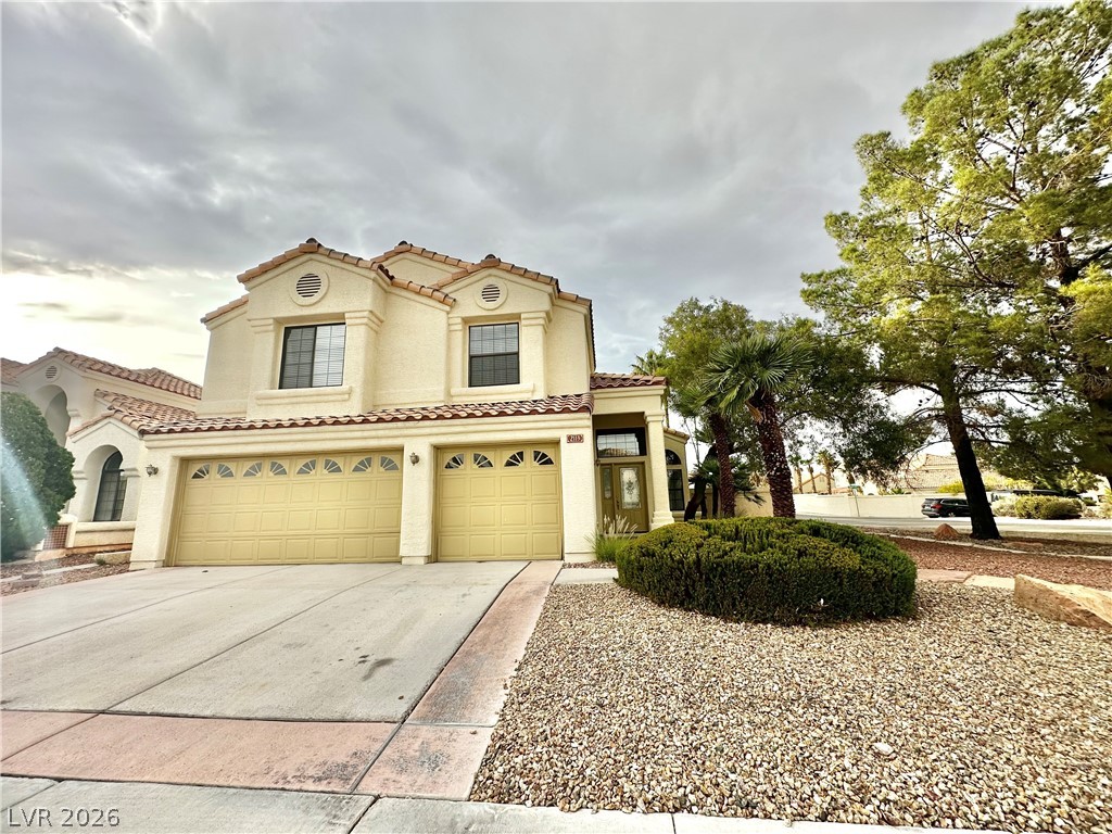 Mediterranean / spanish house with an attached garage, stucco siding, concrete driveway, and a tile roof
