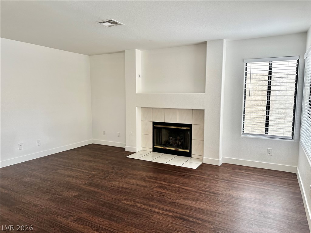 2113 Rico Peak Court Las Vegas, NV 89128 - Photo 11 of 53 Unfurnished living room featuring dark wood-type flooring and a tile fireplace