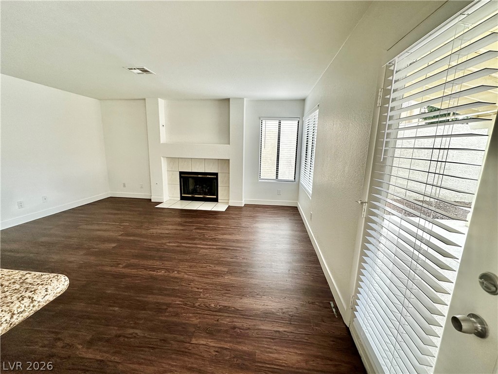 2113 Rico Peak Court Las Vegas, NV 89128 - Photo 12 of 53 Unfurnished living room featuring dark wood-style flooring and a tiled fireplace