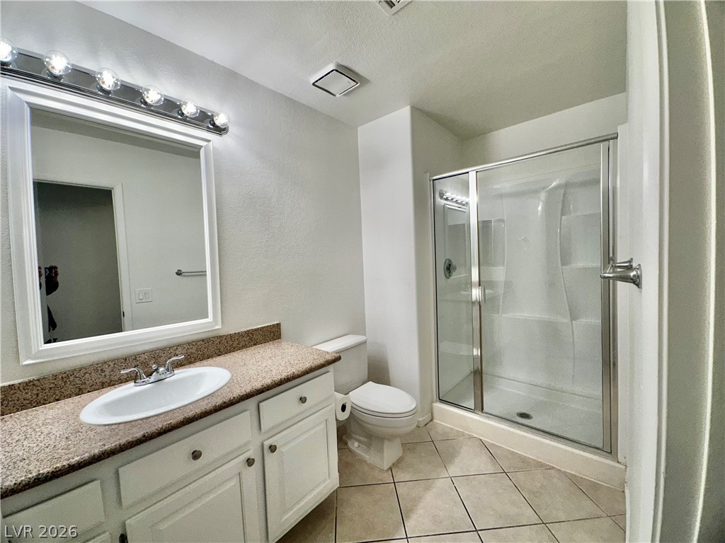 2113 Rico Peak Court Las Vegas, NV 89128 - Photo 17 of 53 Full bath featuring a shower stall, vanity, light tile patterned floors, and a textured ceiling