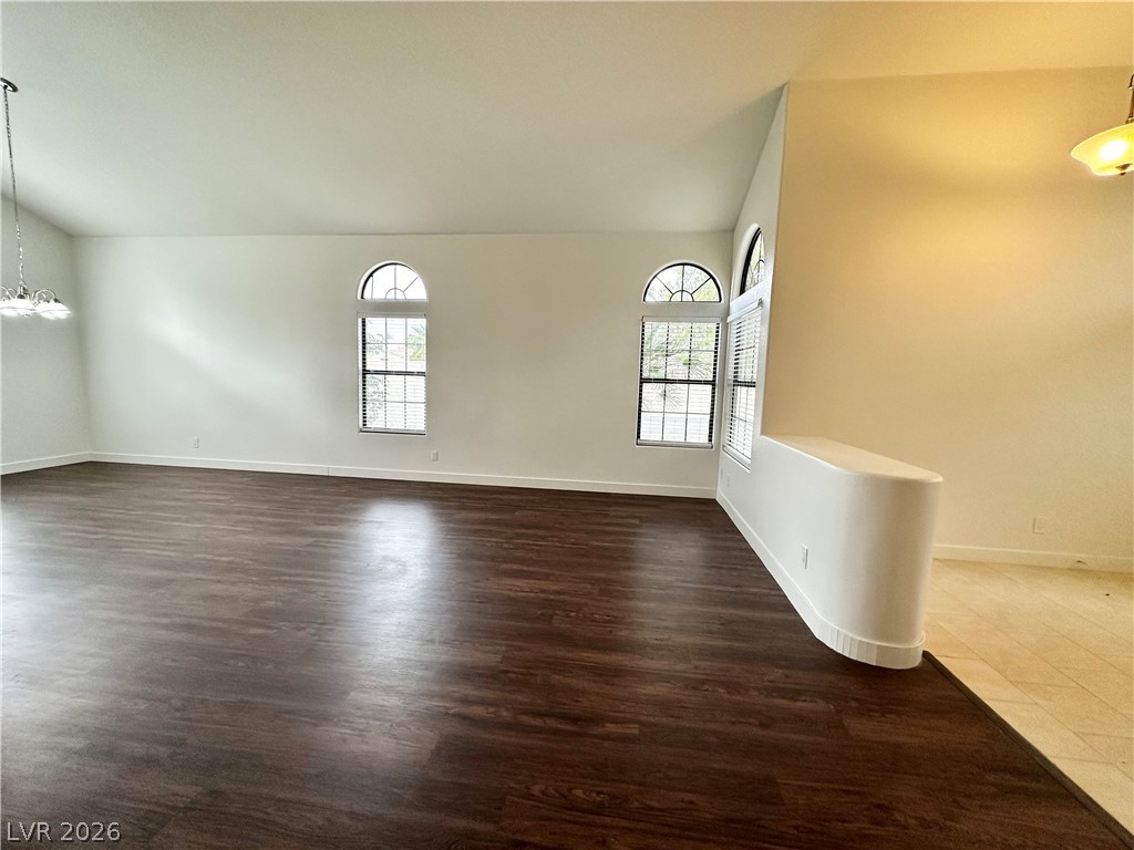 2113 Rico Peak Court Las Vegas, NV 89128 - Photo 23 of 53 Empty room featuring vaulted ceiling, hanging lights, dark wood-type flooring, and healthy amount of natural light
